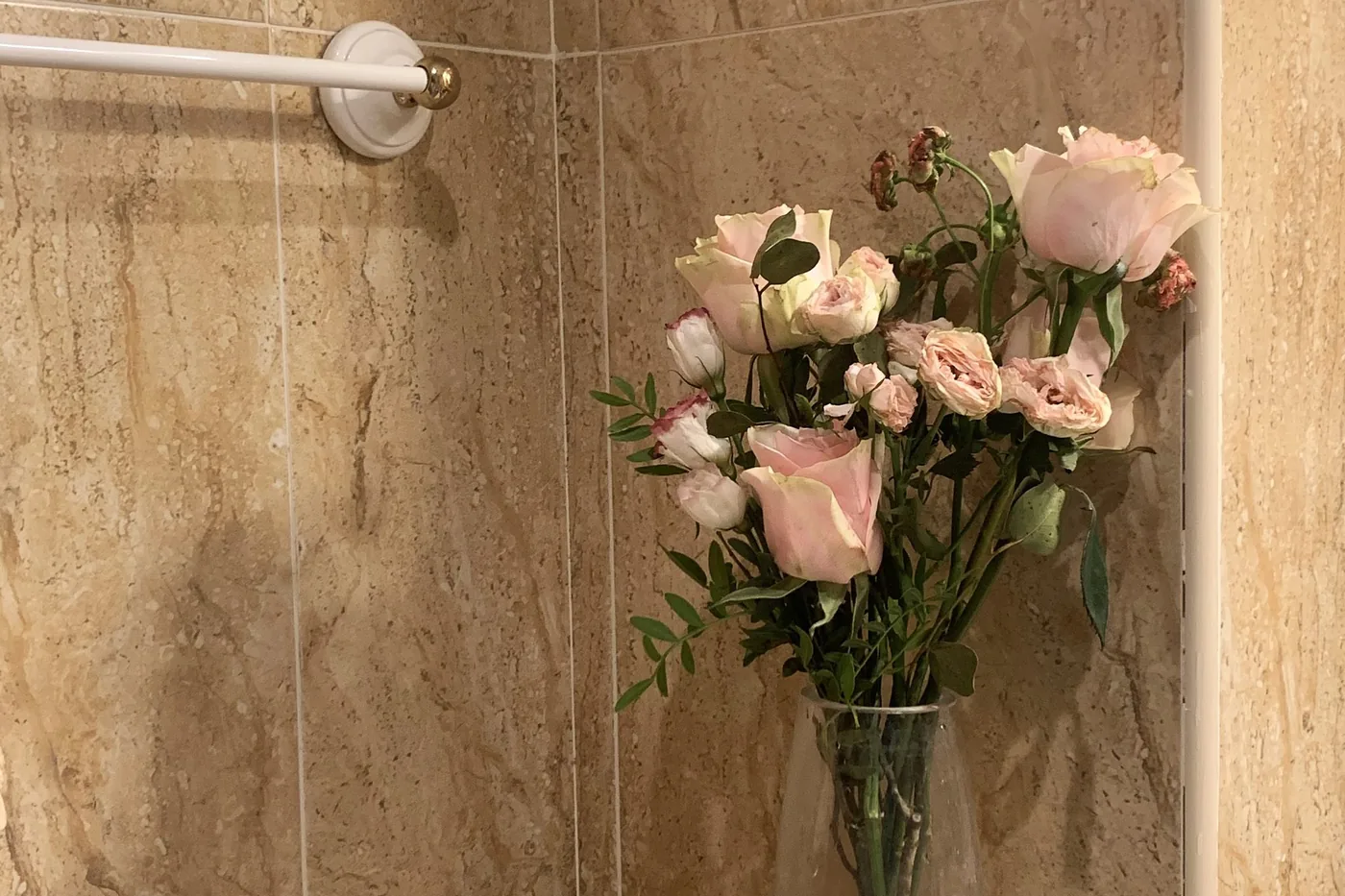 Mermer banyo duvarında havluluk ve çiçek düzenlemesi