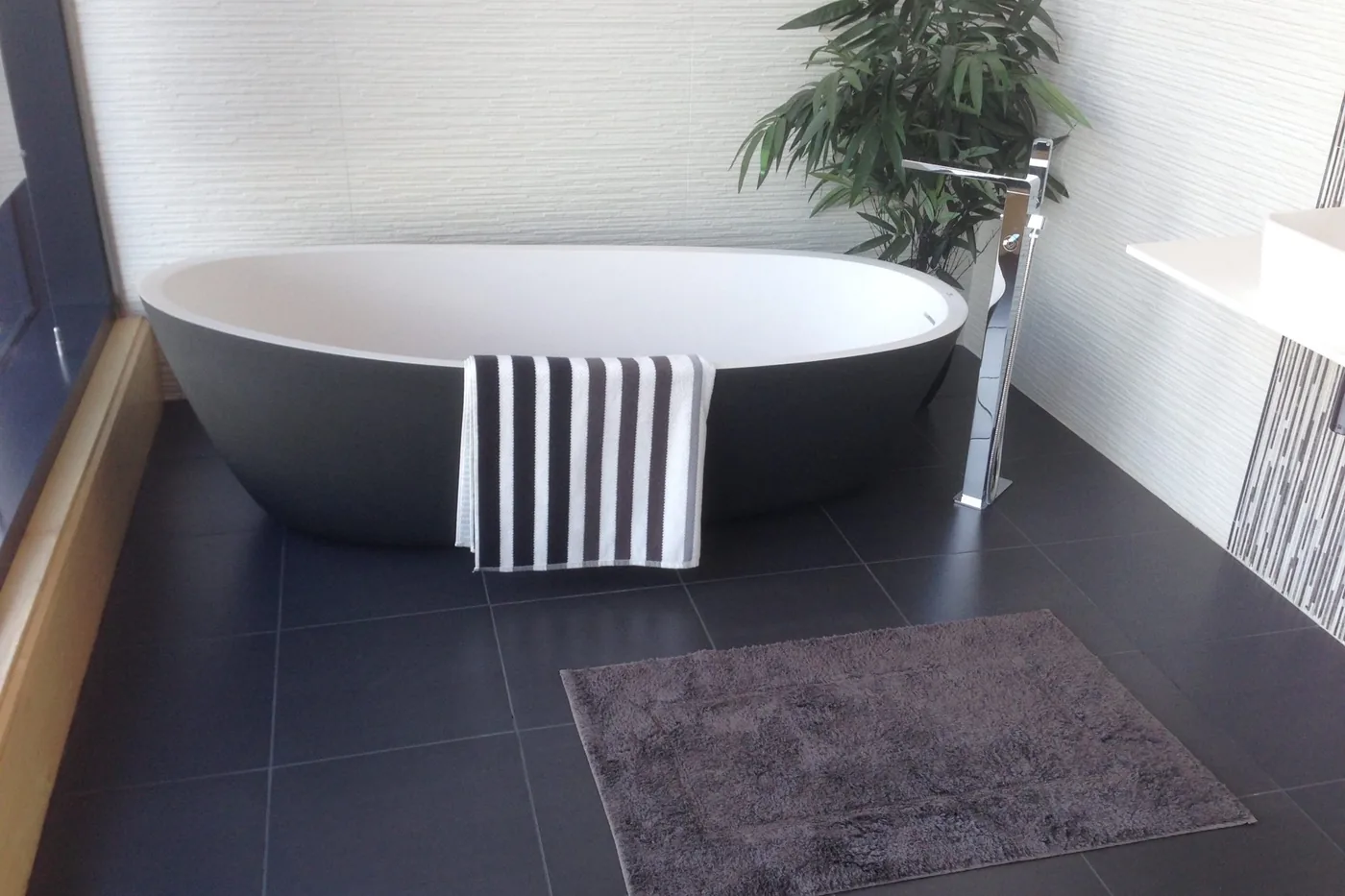Otel banyosunda küvet, havlu ve banyo paspası düzeni